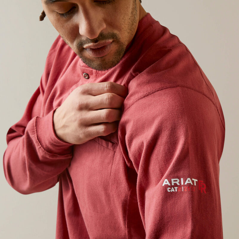 Side view of a man wearing brick Ariat FR Henley Shirt